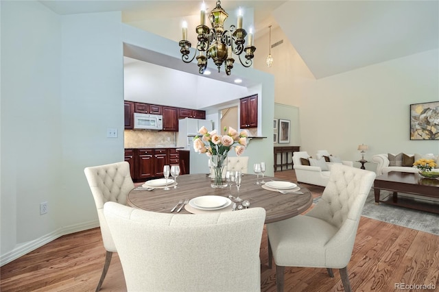 dining space featuring a chandelier, light hardwood / wood-style floors, and high vaulted ceiling