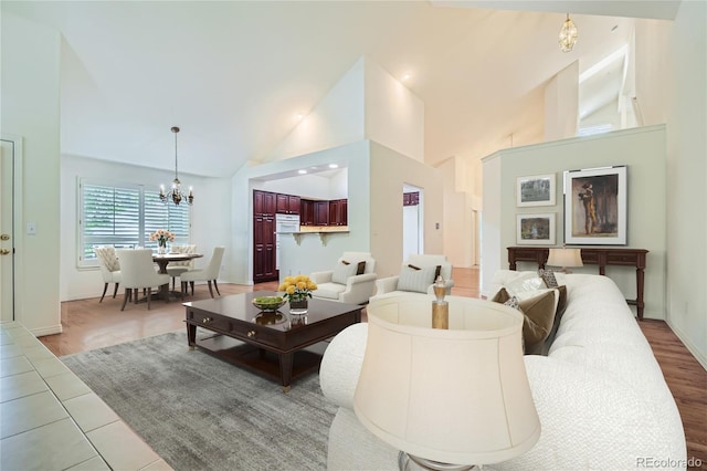 living room featuring tile patterned flooring, high vaulted ceiling, and a notable chandelier