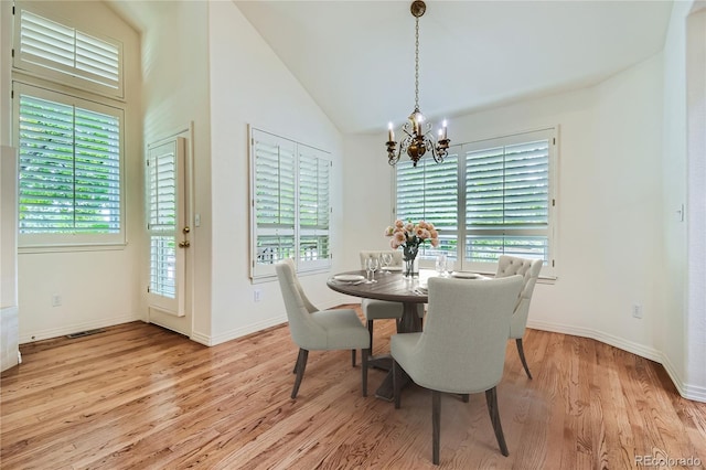 dining area featuring light hardwood / wood-style floors, vaulted ceiling, a healthy amount of sunlight, and a notable chandelier