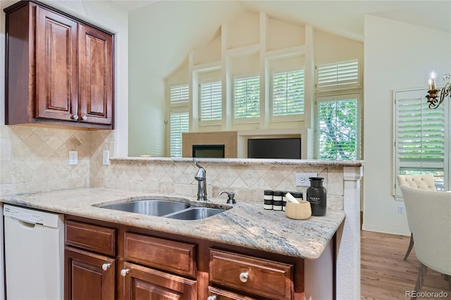 kitchen featuring light stone countertops, sink, white dishwasher, and vaulted ceiling