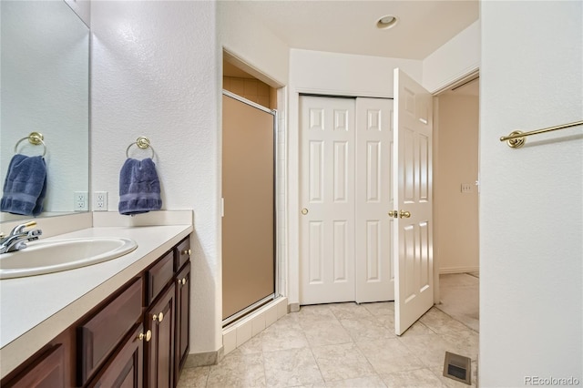 bathroom featuring a shower with door and vanity