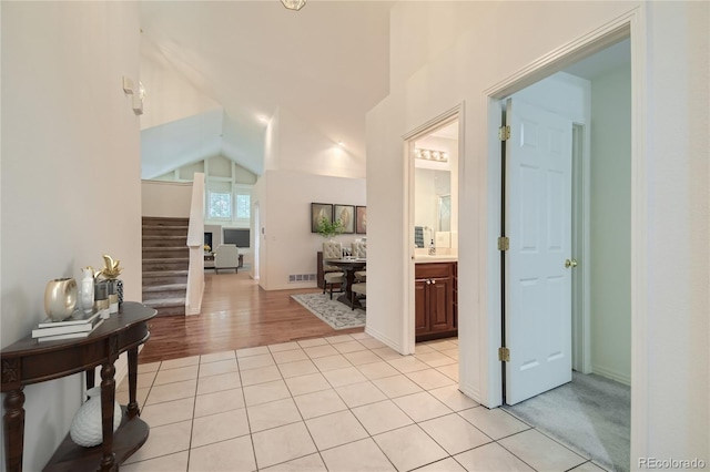 hallway featuring light tile patterned floors and lofted ceiling