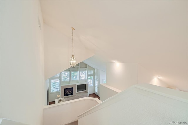 staircase with a tile fireplace, wood-type flooring, vaulted ceiling, and a notable chandelier