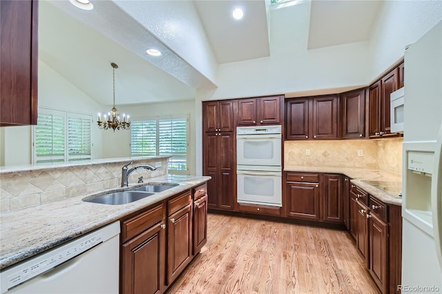 kitchen featuring decorative backsplash, white appliances, sink, an inviting chandelier, and hanging light fixtures