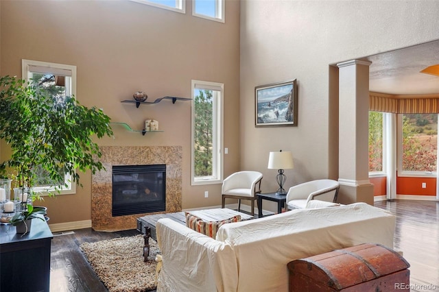 living room with a high end fireplace, a wealth of natural light, ornate columns, and dark hardwood / wood-style flooring