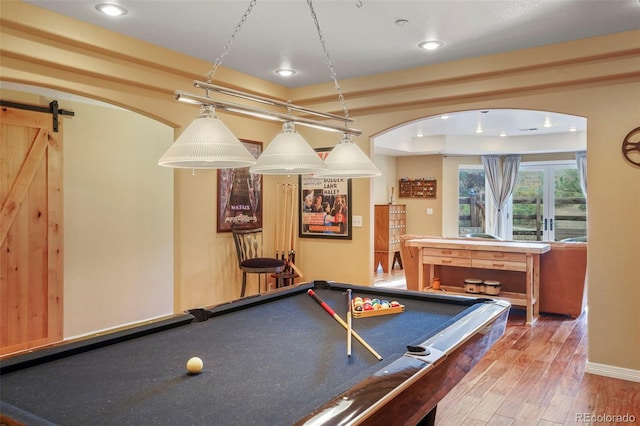 recreation room with a barn door, pool table, and wood-type flooring