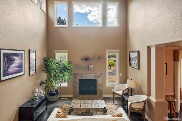 living room with a high end fireplace, hardwood / wood-style flooring, and a towering ceiling