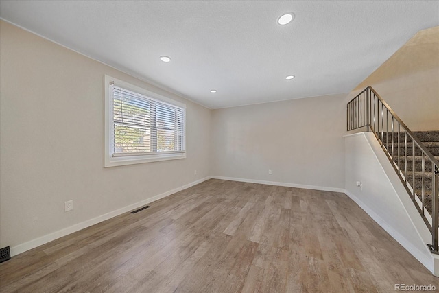 empty room featuring a textured ceiling and light hardwood / wood-style flooring