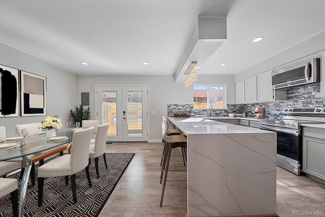 1827 Quail St Unit 3, Lakewood, CO 80215 - kitchen featuring stainless steel appliances, a breakfast bar, backsplash, light stone countertops, and a sink