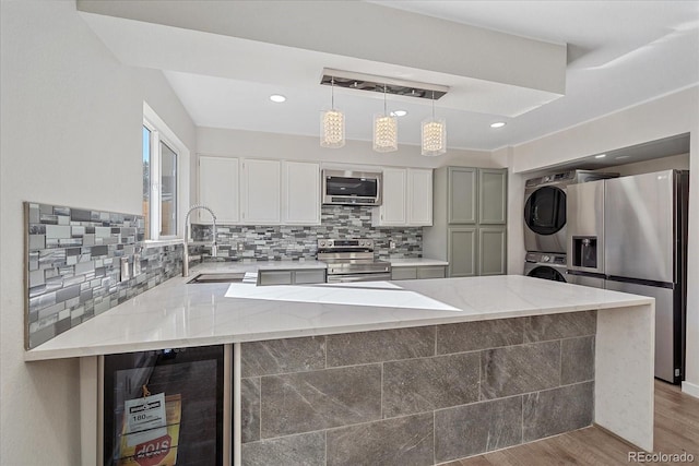 kitchen with appliances with stainless steel finishes, backsplash, light stone counters, light hardwood / wood-style floors, and stacked washer and dryer