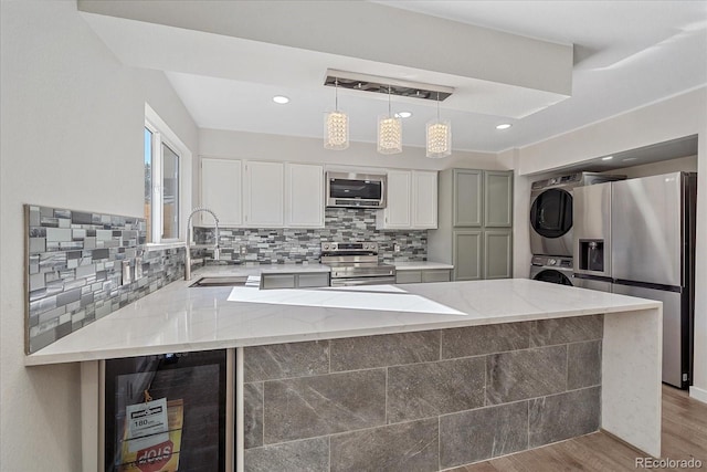 1827 Quail St Unit 3, Lakewood, CO 80215 - kitchen with stacked washer and clothes dryer, appliances with stainless steel finishes, wine cooler, a sink, and a peninsula