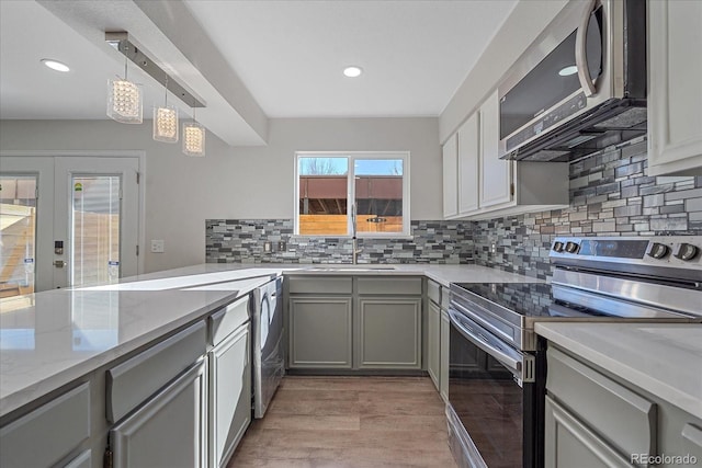 kitchen with gray cabinetry, french doors, hanging light fixtures, light hardwood / wood-style flooring, and appliances with stainless steel finishes