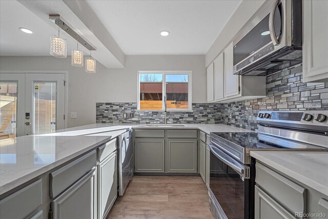 1827 Quail St Unit 3, Lakewood, CO 80215 - kitchen featuring appliances with stainless steel finishes, a sink, gray cabinetry, backsplash, and light stone counters