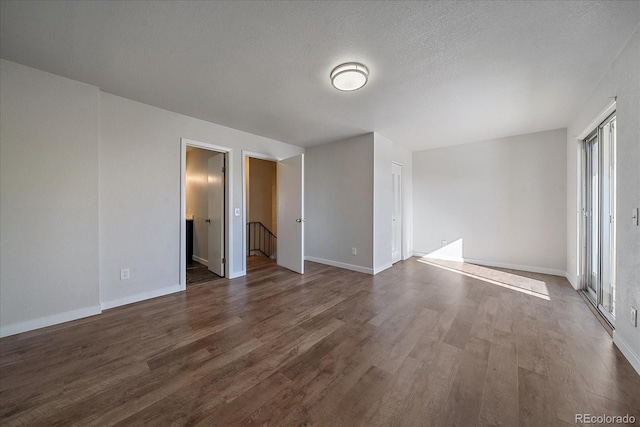 unfurnished room with dark hardwood / wood-style flooring, a textured ceiling, and a wealth of natural light