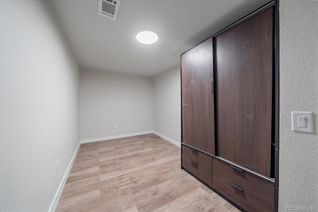 unfurnished bedroom with light wood-type flooring and a closet