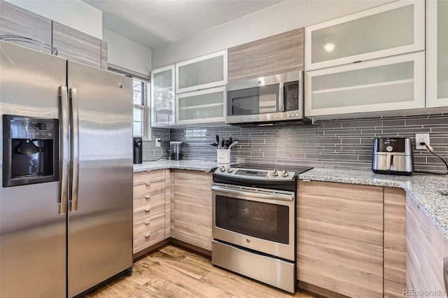 1818 S Quebec Way Unit 11-8, Denver, CO 80231 - kitchen featuring backsplash, stainless steel appliances, light wood-type flooring, and light stone countertops
