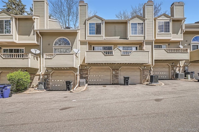 1818 S Quebec Way Unit 11-8, Denver, CO 80231 - rear view of house with an attached garage, central AC unit, and a chimney