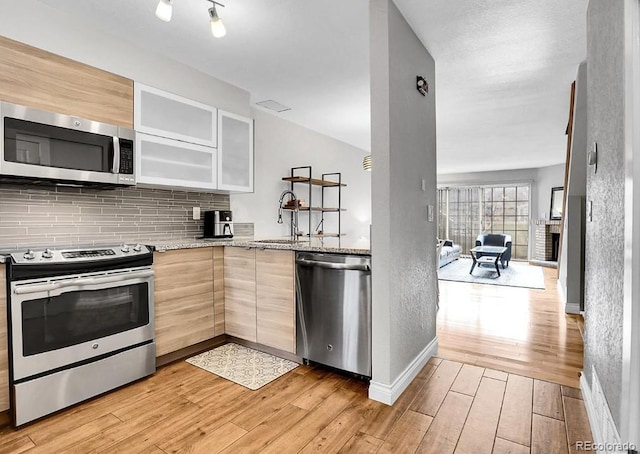 1818 S Quebec Way Unit 11-8, Denver, CO 80231 - kitchen featuring stainless steel appliances, decorative backsplash, light stone countertops, light wood-type flooring, and light brown cabinets