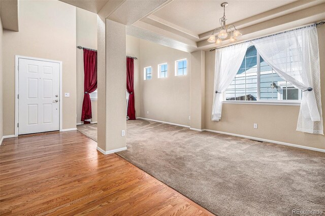 entrance foyer with a tray ceiling, an inviting chandelier, and hardwood / wood-style flooring