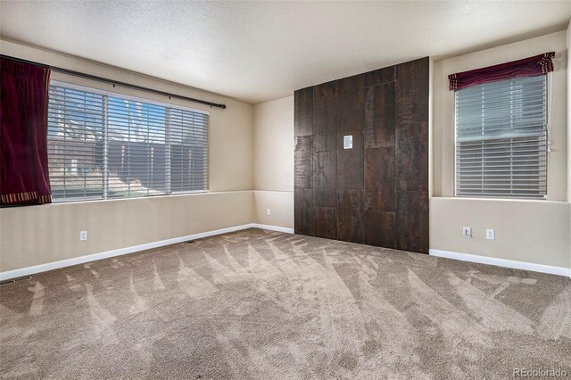 spare room with a textured ceiling and carpet floors