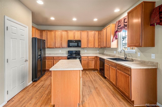 kitchen featuring light wood-style flooring, a kitchen island, light countertops, black appliances, and a sink