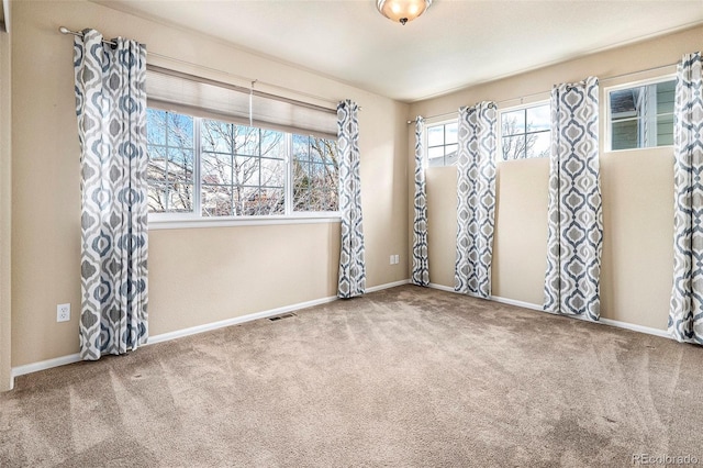 empty room featuring baseboards, visible vents, and carpet flooring