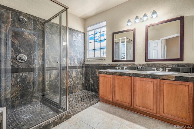 full bathroom with double vanity, tile patterned flooring, a marble finish shower, and a sink