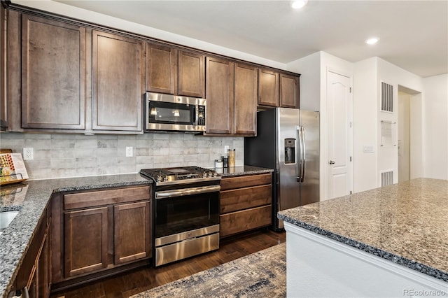 kitchen featuring dark wood finished floors, stainless steel appliances, dark brown cabinets, and visible vents