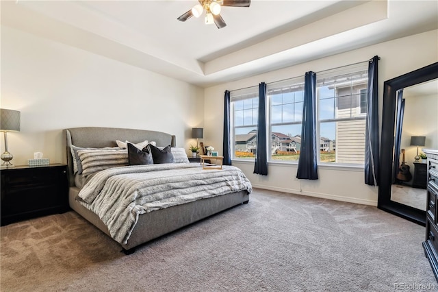bedroom featuring a ceiling fan, carpet flooring, a tray ceiling, and baseboards