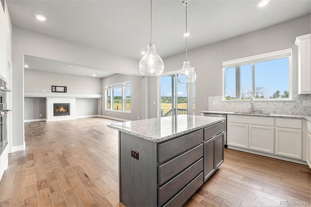 7293 Xenophon Ct, Arvada, CO 80004 - kitchen with white cabinetry, recessed lighting, backsplash, light wood finished floors, and a kitchen island