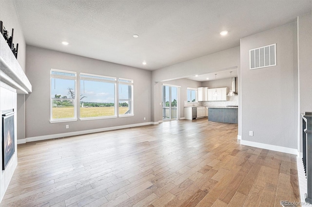 7293 Xenophon Ct, Arvada, CO 80004 - unfurnished living room with a glass covered fireplace, light wood-type flooring, and recessed lighting