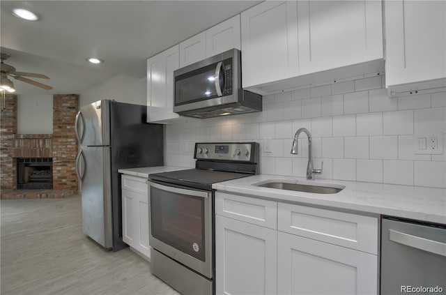 kitchen featuring sink, white cabinets, decorative backsplash, light stone counters, and stainless steel appliances