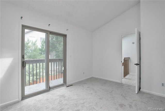 spare room with vaulted ceiling, light carpet, and a textured ceiling