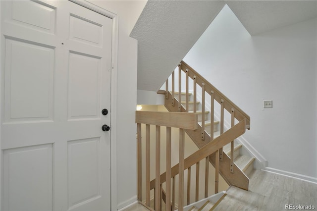 staircase featuring hardwood / wood-style floors and a textured ceiling