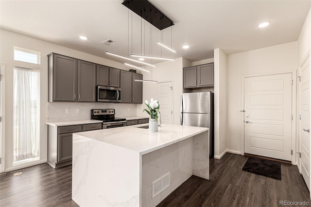 3805 N Himalaya Rd Unit 1, Denver, CO 80249 - kitchen featuring gray cabinets, stainless steel appliances, dark wood-type flooring, decorative light fixtures, and a center island with sink