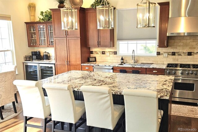 24733 E Park Crescent Dr, Aurora, CO 80016 - kitchen featuring wall chimney range hood, appliances with stainless steel finishes, a chandelier, and healthy amount of natural light
