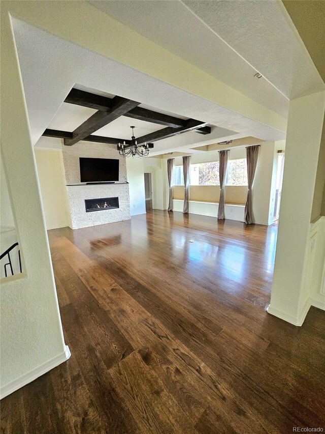 24733 E Park Crescent Dr, Aurora, CO 80016 - unfurnished living room featuring wood finished floors, beamed ceiling, a fireplace, a chandelier, and a textured ceiling