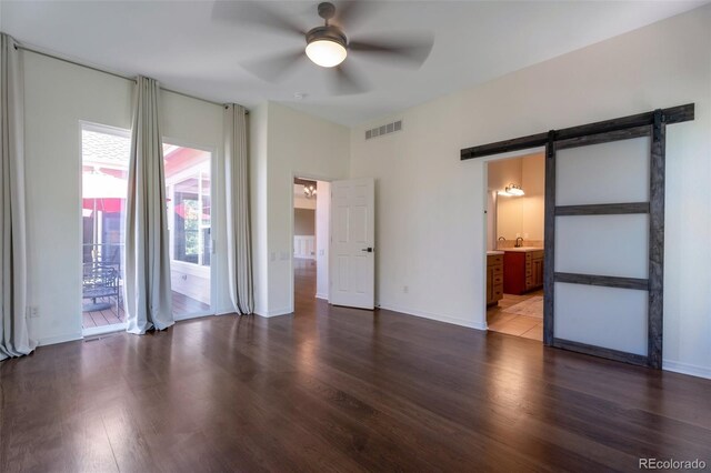 24733 E Park Crescent Dr, Aurora, CO 80016 - unfurnished bedroom with a barn door, wood finished floors, access to exterior, connected bathroom, and a ceiling fan