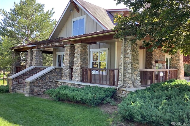 24733 E Park Crescent Dr, Aurora, CO 80016 - craftsman house featuring stone siding, board and batten siding, a porch, and a front lawn