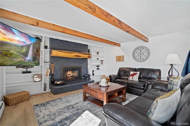 living room with a brick fireplace, baseboard heating, light wood-type flooring, and beamed ceiling