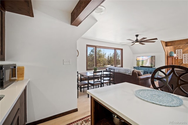 kitchen with light wood-type flooring, ceiling fan, and vaulted ceiling with beams