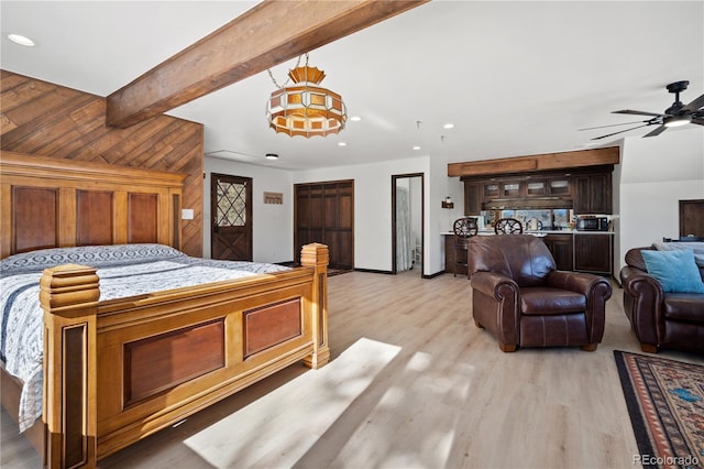 bedroom featuring light wood-type flooring, wood walls, ceiling fan, and beamed ceiling