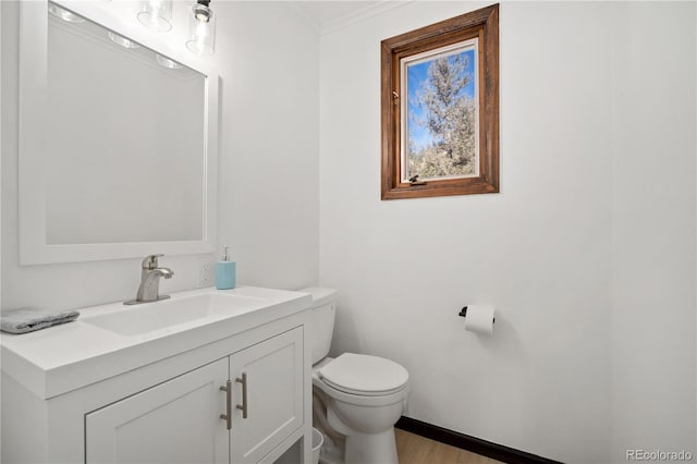 bathroom featuring hardwood / wood-style flooring, crown molding, vanity, and toilet