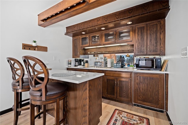 bar featuring sink, light wood-type flooring, beamed ceiling, and dark brown cabinetry