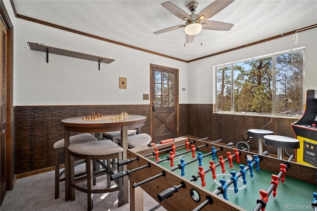 rec room with ceiling fan, crown molding, and carpet flooring