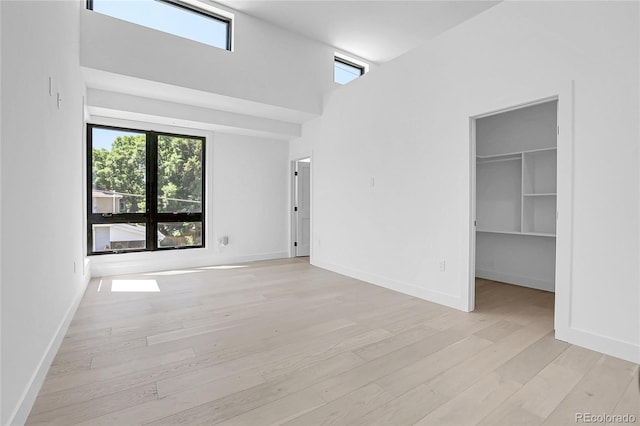 1491 S York St, Denver, CO 80210 - unfurnished bedroom featuring multiple windows, light wood-style floors, a spacious closet, and a high ceiling