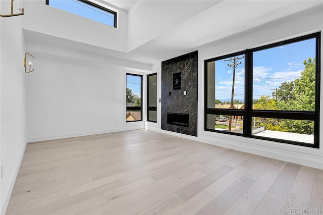 1491 S York St, Denver, CO 80210 - unfurnished living room with light wood finished floors, a towering ceiling, and a high end fireplace