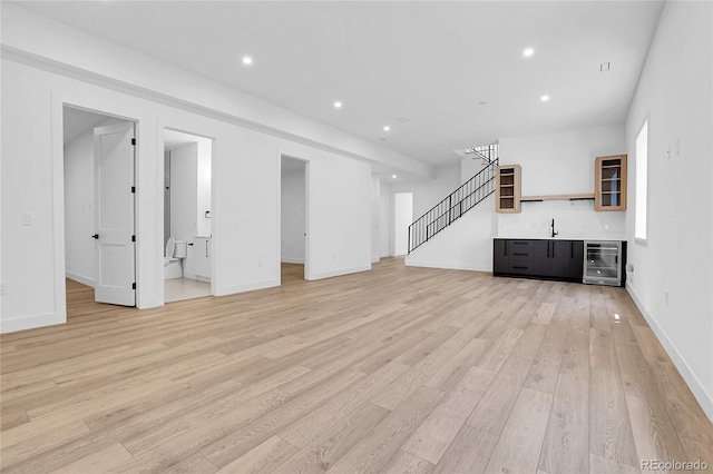 1491 S York St, Denver, CO 80210 - unfurnished living room featuring beverage cooler, light wood-style flooring, stairway, recessed lighting, and bar