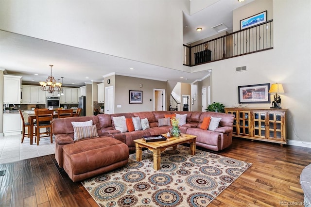 living room with light wood-type flooring, a chandelier, and a high ceiling