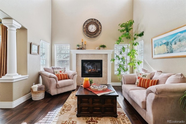 sitting room with a tiled fireplace, decorative columns, and dark hardwood / wood-style flooring